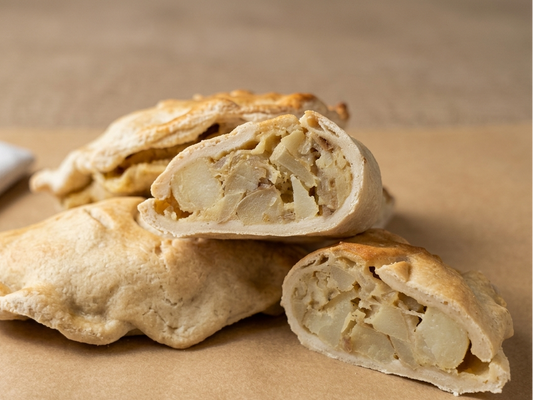 Pastry with a slice cut open, revealing filling on a brown surface